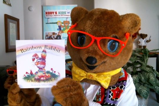 Kody O'Bear holding Book of the Month Rainbow Rabbit.