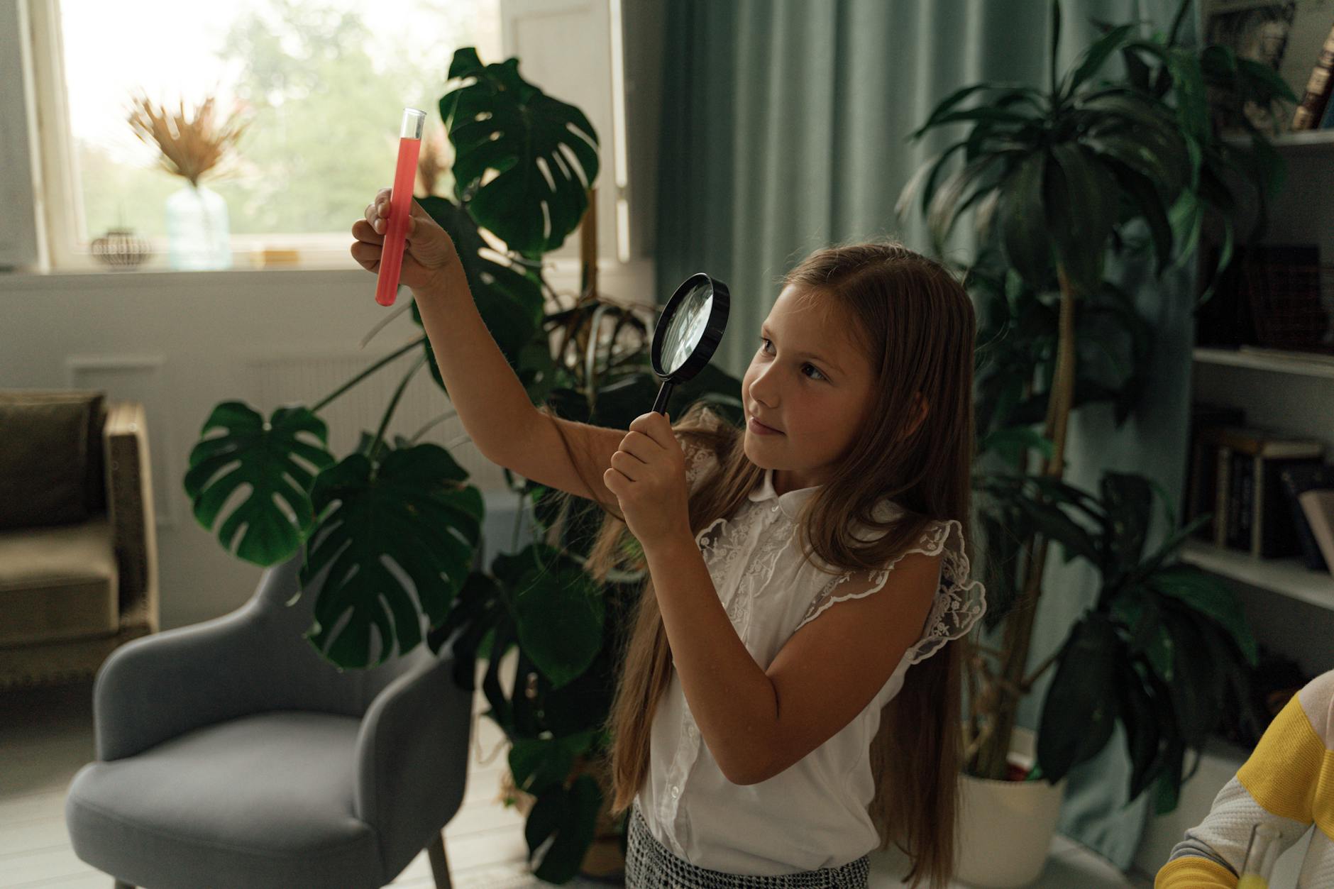 a girl in white blouse observing the chemical on the test tube using a magnifying glass